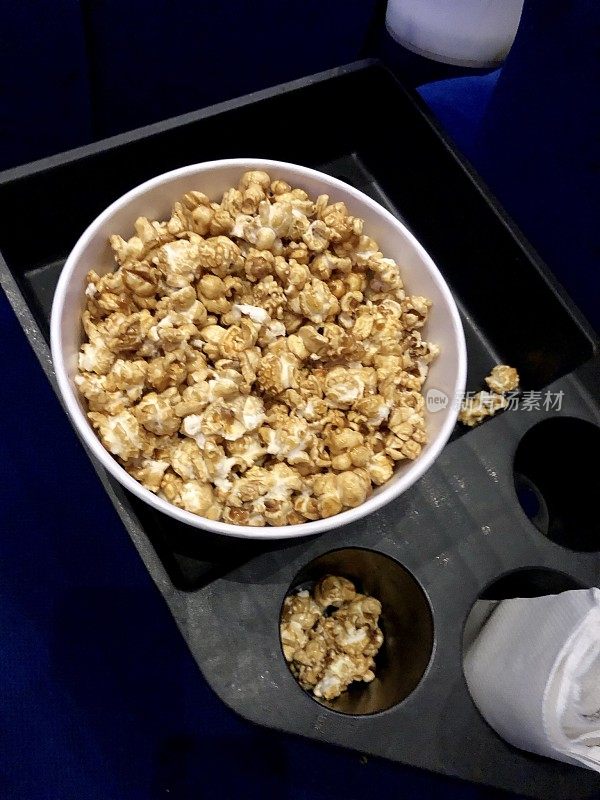 电影院里的一桶爆米花，电影小吃。焦糖/焦糖太妃爆米花作为电影零食纸杯，高视化